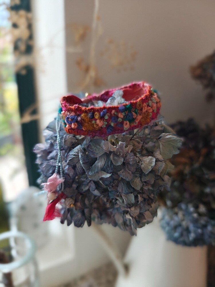Hand-embroidered cuff resting on dried hydrangea